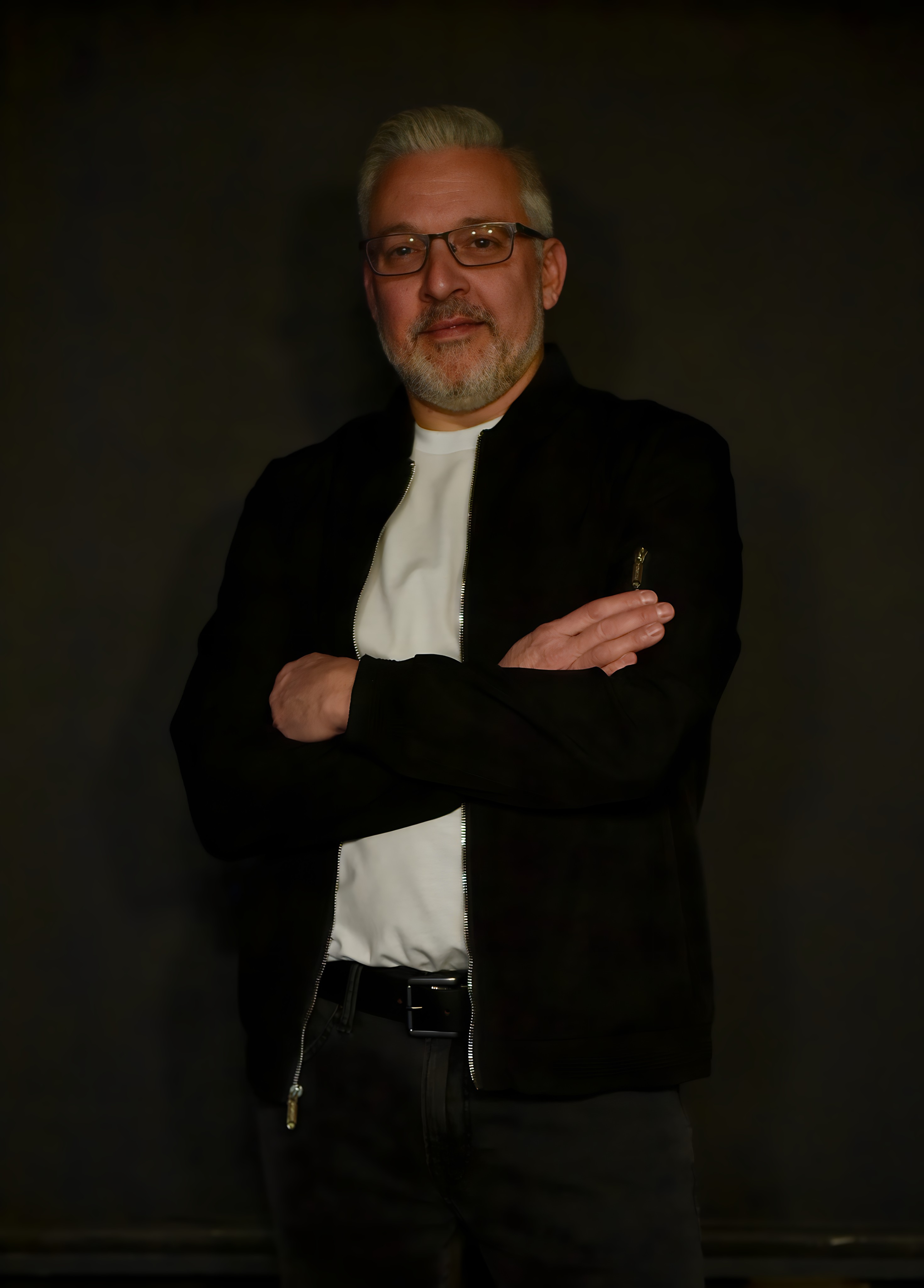 Bill in a dark jacket and white shirt with his arms folded