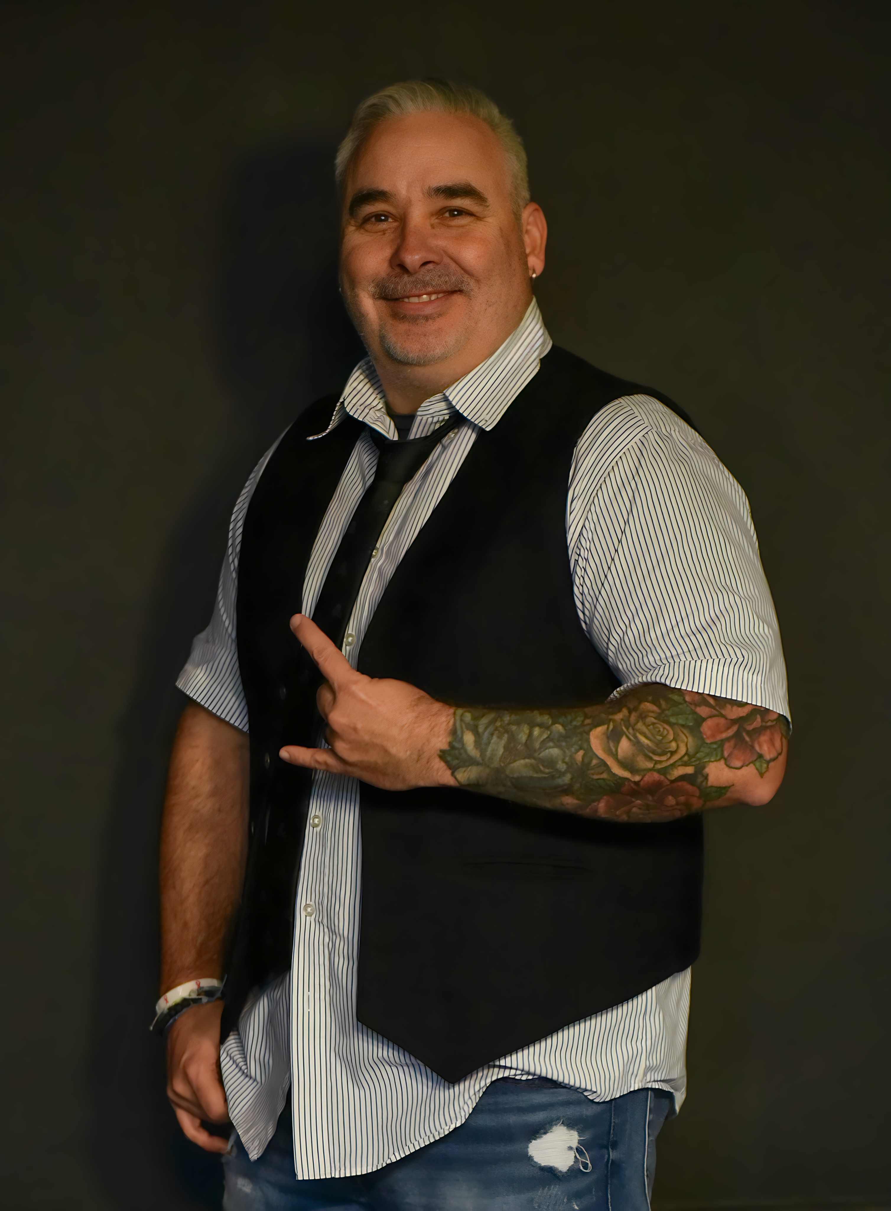 Tony smiling in a striped shirt and dark vest
