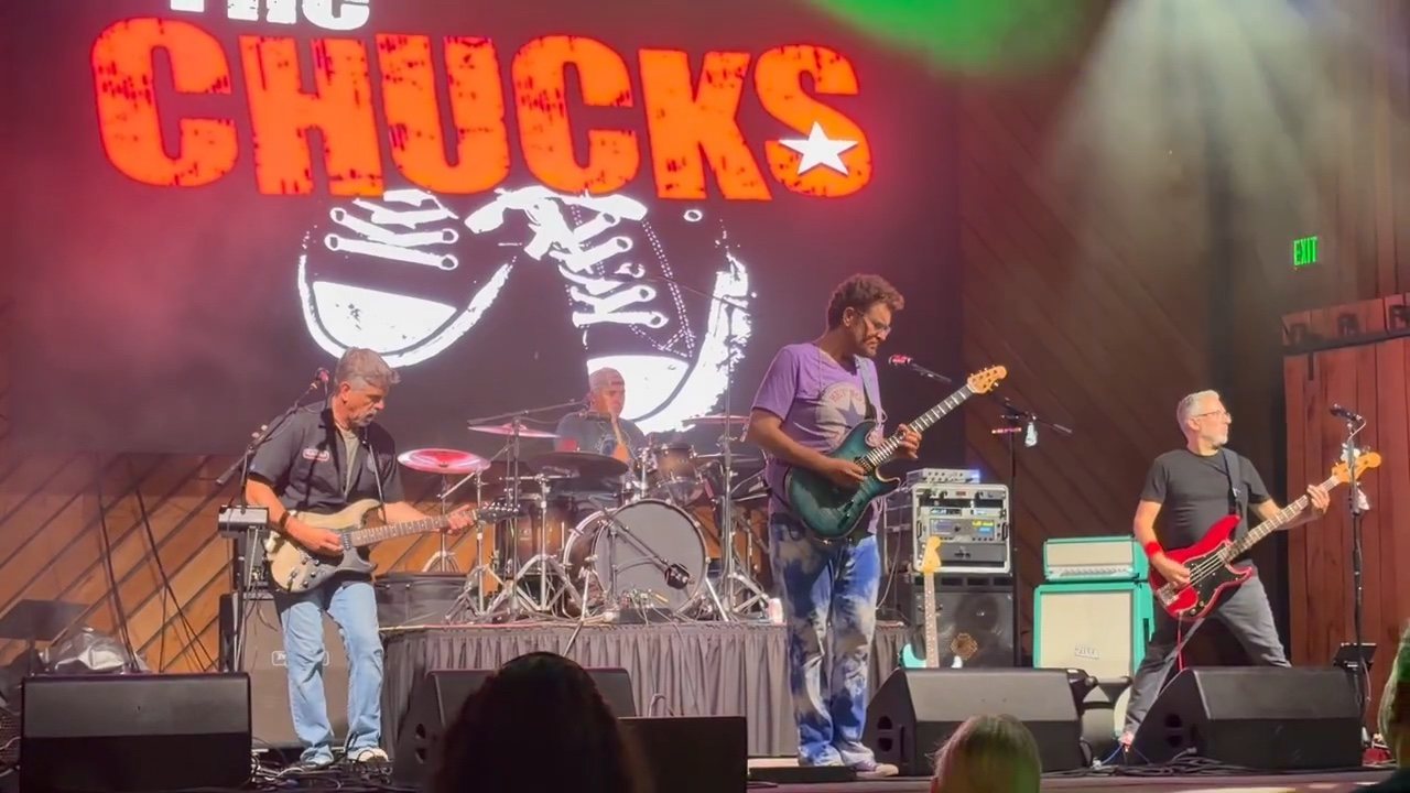 The Chucks current lineup performing beneath their logo on a large theater stage