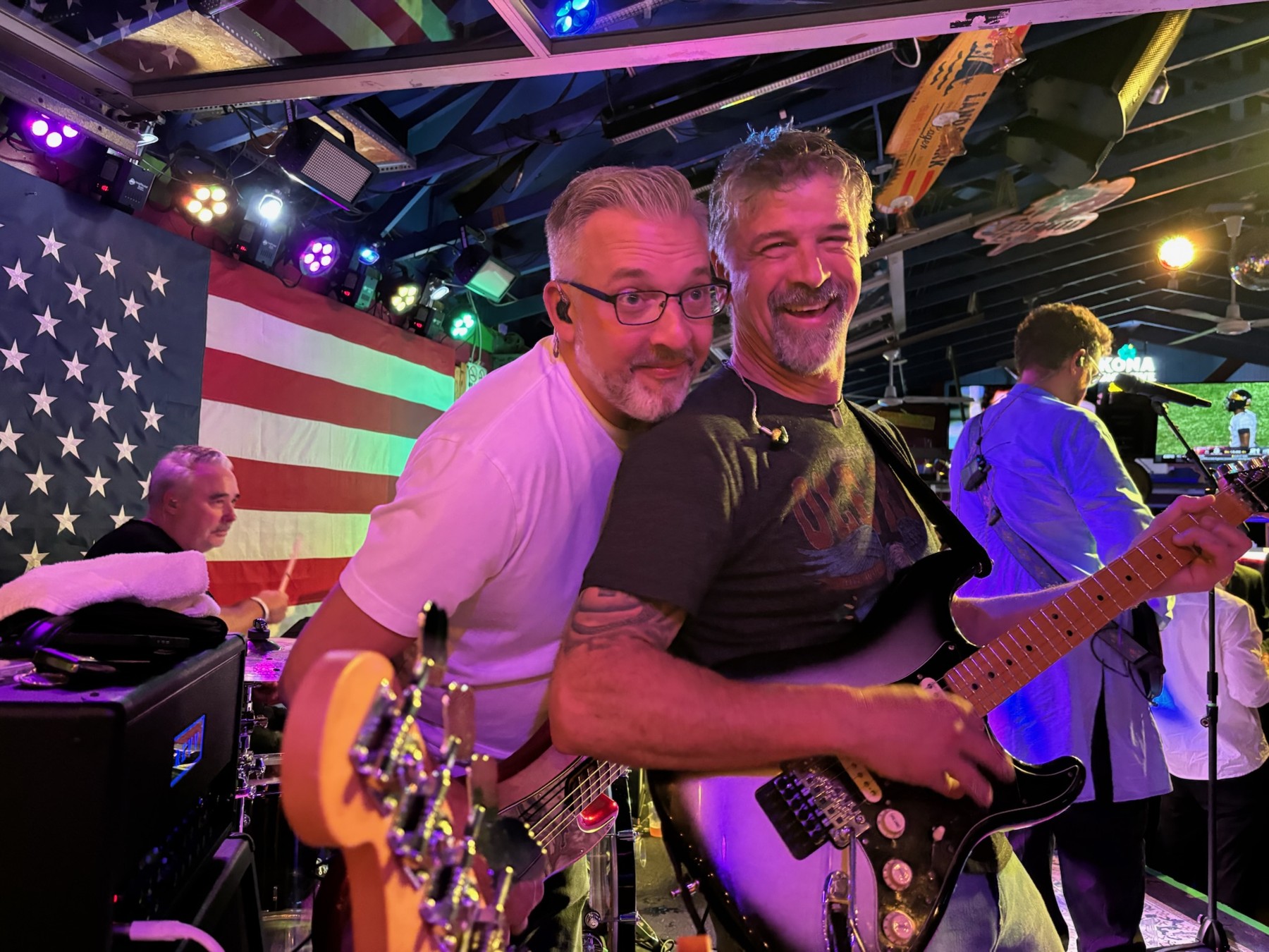 Two Chucks guitarists sharing a laugh mid-song, with the band behind them