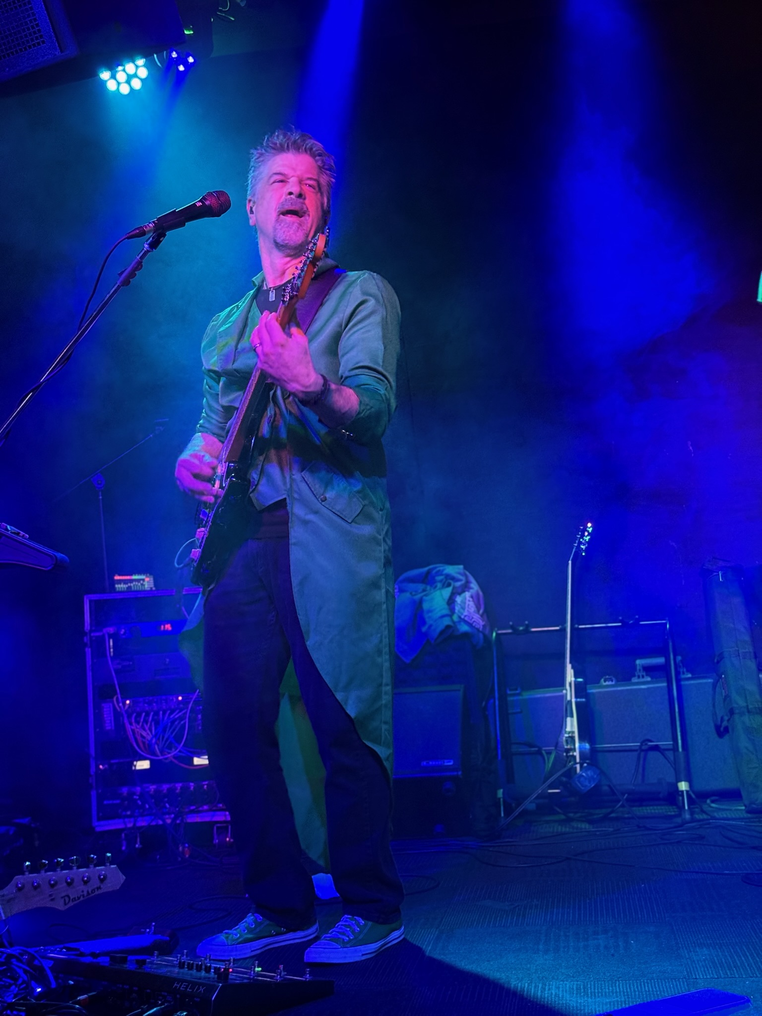 Joe leaning into a guitar solo beneath deep blue stage lights