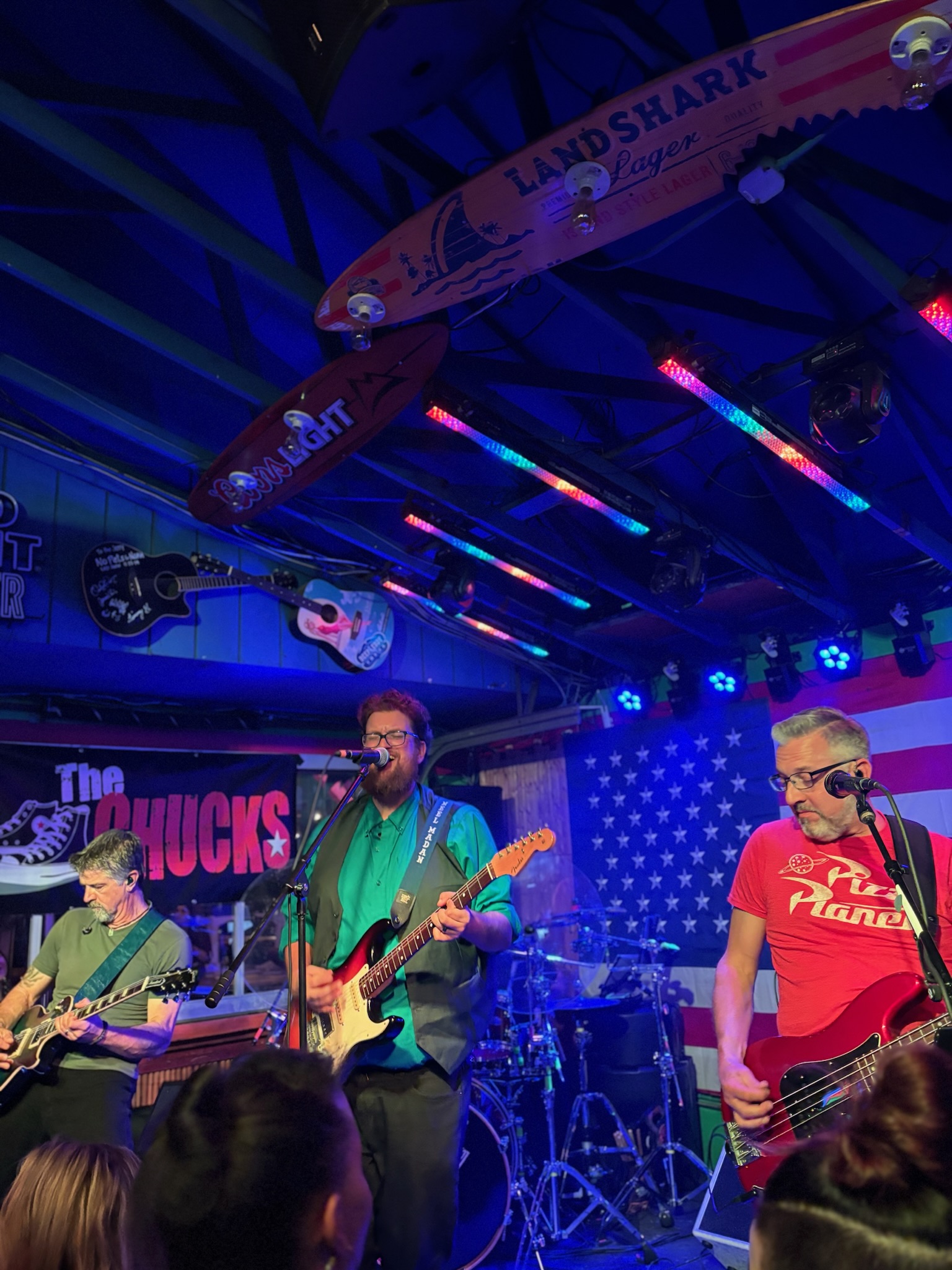 The Chucks performing together beneath saturated magenta lights
