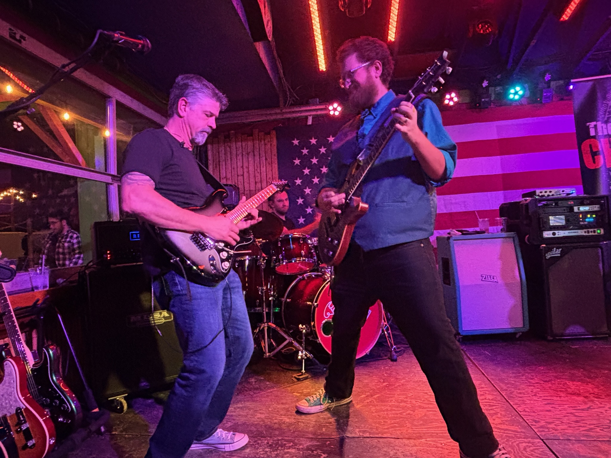 Two guitarists facing off while Tony drives the beat behind them