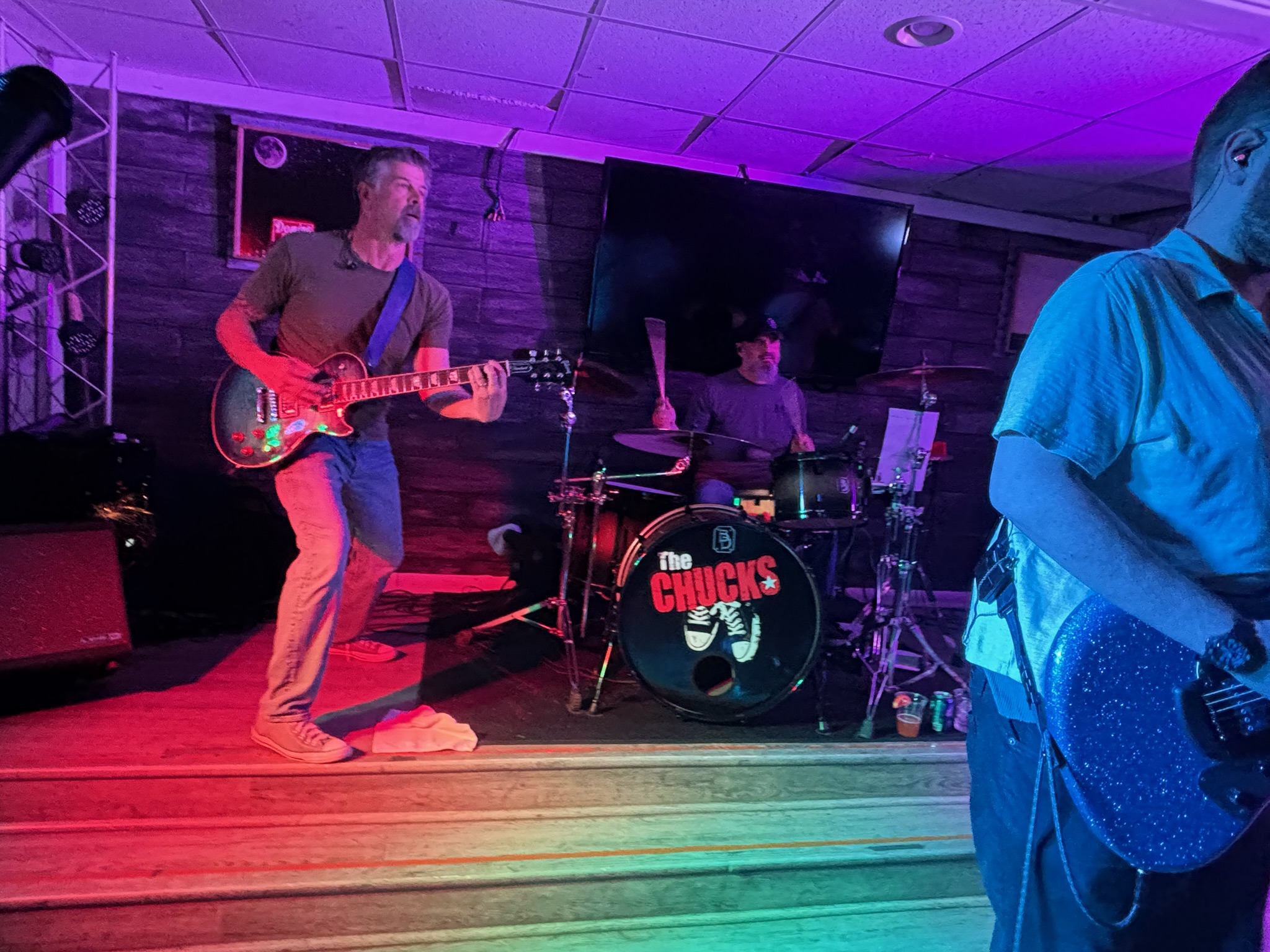 Joe playing guitar with Tony visible behind the drum kit