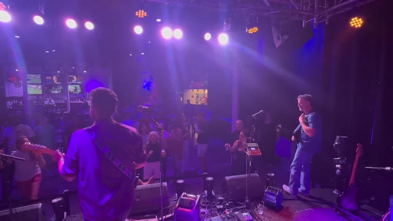The Chucks looking out from the stage toward a dance floor under purple lights